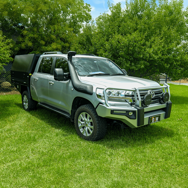 Load image into Gallery viewer, A silver Toyota LandCruiser 200 Series dual cab ute featuring a DMW Deluxe Alloy Tray with compact black canopy, photographed on green grass in a park setting. Outfitted with a snorkel, bull bar, and driving lights, this build is ideal for off-road touring with secure rear storage and protection.
