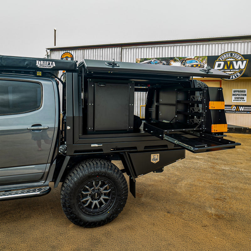 Load image into Gallery viewer, A detailed look at a DMW Deluxe canopy system with the side door open, revealing a premium internal fit-out including slide-out storage, drawers, and kitchen modules. Mounted on a dual cab ute, this setup is ideal for overlanding, remote camping, and organised adventure travel.
