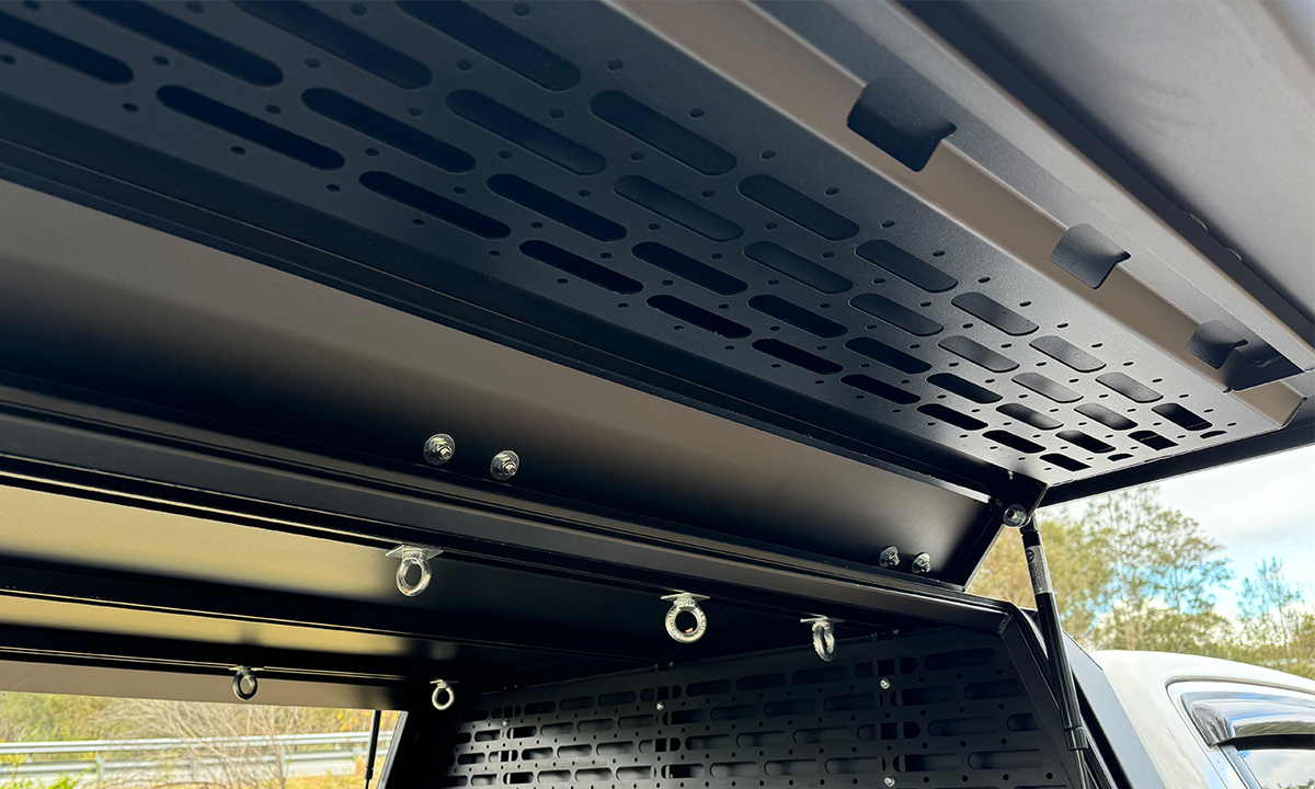 Close-up view of the inside canopy door of a DMW tub replacement setup, showcasing a precision-cut MOLLE panel, multiple tie-down rings, and gas strut supports. Designed for modular mounting and secure storage, this canopy door system is ideal for overland gear, trade tools, or 4WD accessories.