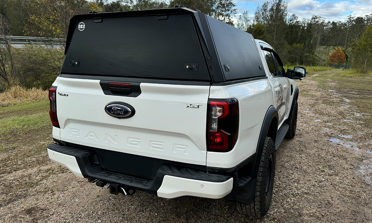 A white Ford Ranger XLT 4x4 shown from the rear with a black DMW tub replacement canopy securely closed. The sleek, low-profile canopy offers streamlined storage while maintaining the factory tailgate, blending utility and modern design for everyday or off-road use.